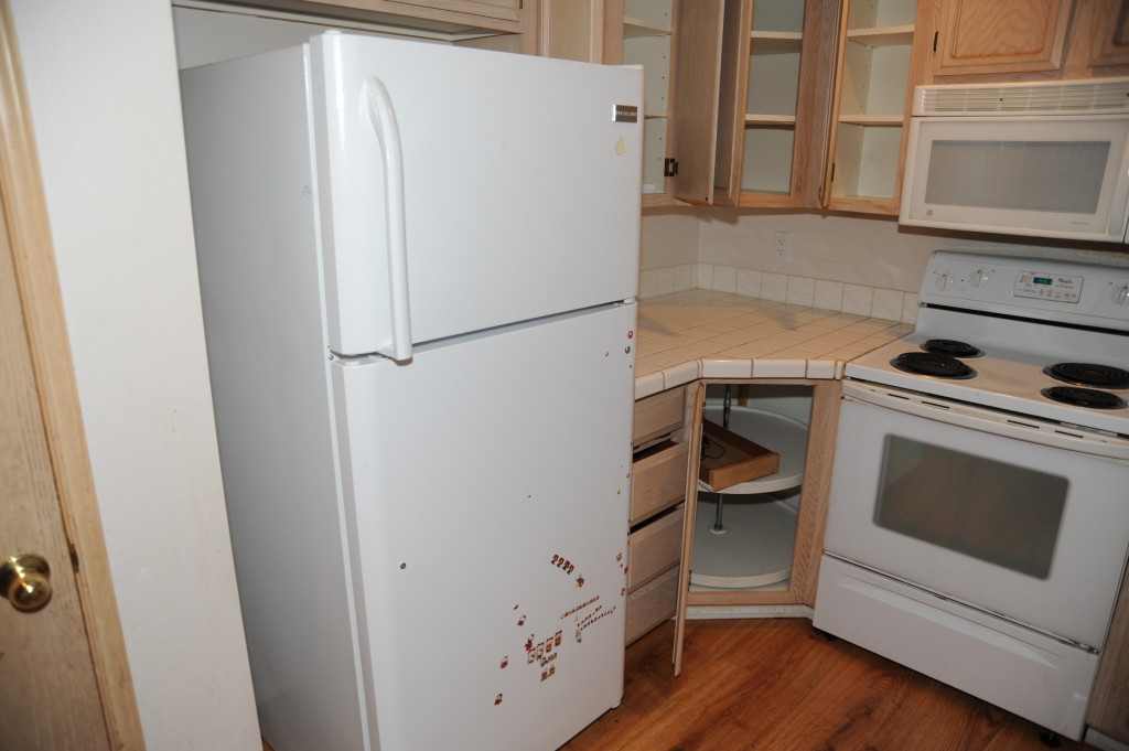 Refrigerator missing a handle and other damage.